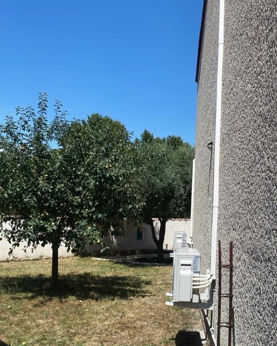 vue large de la façade de la maison avec une partie du jardin montrant la manière dont l'élément extérieur de l'installation du multisplit à orange de fond dans le décor