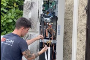 L'installateur de gainable à Orange MP Clim travaillant sur l'unité extérieur de ce système de climatisation.